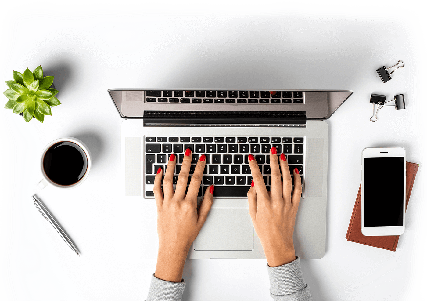 Ein Arbeitsbereich von oben. Eine Frau hat die Hände auf einer Laptop Tastatur